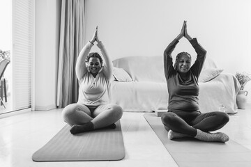 Wall Mural - Mother and daughter doing yoga exercises at home together at home - Focus on hands - Black and white editing