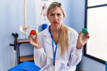 Poster - Beautiful woman holding strength ball for hand rehabilitation skeptic and nervous, frowning upset because of problem. negative person.