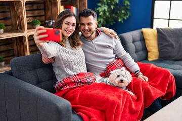 Wall Mural - Man and woman making selfie by the smartphone sitting on sofa with dog at home