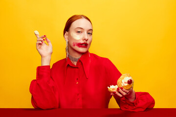 Wall Mural - Whipped cream. Beautiful young girl in red shirt with smudged red lipstick after eating cake over yellow studio background. Food pop art photography. Complementary colors. Concept of art, beauty, food