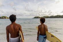 Indonesia, Lombok, Rear View Of Surfers Looking At Sea From Beach