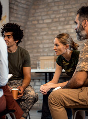 Wall Mural - Female soldier talking with diverse group of veterans during PTSD support group.