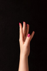 Wall Mural - Female hand with beautiful manicure - viva magenta, pink nails on dark black background