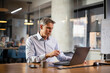 © JustLife - Businessman working with laptop at office. Businessman sitting at office desk working on laptop computer.