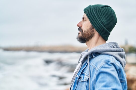 young bald man breathing with closed eyes at seaside