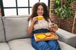 © Krakenimages.com - Young beautiful hispanic woman having breakfast sitting on sofa at home
