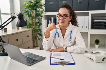 Poster - Young hispanic woman wearing doctor uniform and stethoscope smiling doing phone gesture with hand and fingers like talking on the telephone. communicating concepts.