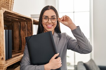 Canvas Print - Young beautiful hispanic woman psychologist smiling confident holding binder at psychology clinic