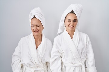 Canvas Print - Middle age woman and daughter wearing white bathrobe and towel winking looking at the camera with sexy expression, cheerful and happy face.