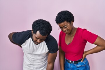 Canvas Print - Young african american couple standing over pink background suffering of backache, touching back with hand, muscular pain