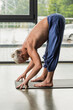 © LIGHTFIELD STUDIOS - shirtless and grey haired man doing standing forward bend pose on yoga mat.