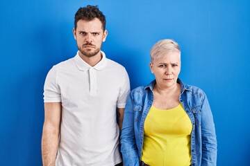 Poster - Young brazilian mother and son standing over blue background skeptic and nervous, frowning upset because of problem. negative person.