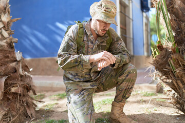 Young hispanic man wearing soldier uniform looking watch at park