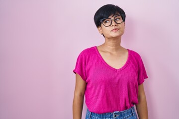 Canvas Print - Young asian woman with short hair standing over pink background smiling looking to the side and staring away thinking.