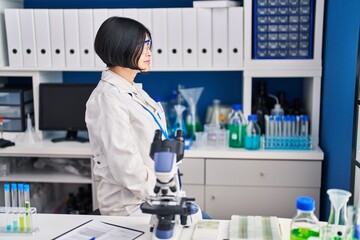 Poster - Young asian woman working at scientist laboratory looking to side, relax profile pose with natural face with confident smile.