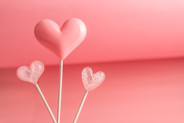 Wall Mural - three Pink Valentine's day heart shape lollipop candy on empty pastel paper background. Love Concept