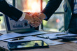 © ArLawKa - Young businessman and businesswoman in investment agreement, two colleague handshake concept. The deal was achieved by mutual funding after a meeting in the financial bureau.