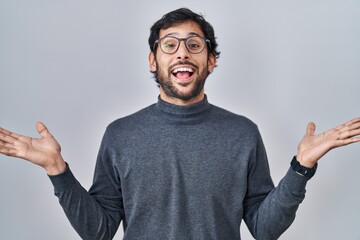 Wall Mural - Handsome latin man standing over isolated background celebrating crazy and amazed for success with arms raised and open eyes screaming excited. winner concept