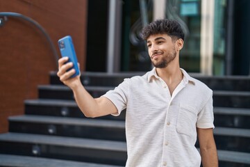 Sticker - Young arab man smiling confident making selfie by the smartphone at street