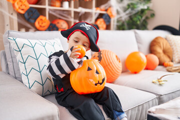 Sticker - Adorable hispanic boy having halloween party holding pumpkin basket at home