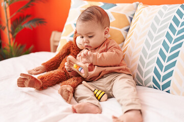 Sticker - Adorable hispanic toddler playing with toy lying on bed at bedroom