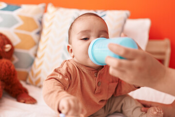 Sticker - Adorable hispanic toddler drinking water sitting on bed at bedroom