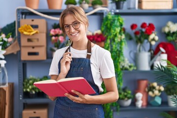 Poster - Young blonde girl florist smiling confident reading book at florist