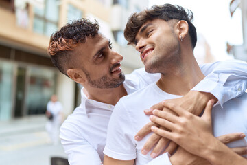 Wall Mural - Two hispanic men couple smiling confident hugging each other at street