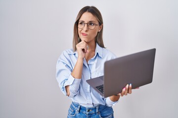 Young woman working using computer laptop thinking worried about a question, concerned and nervous with hand on chin