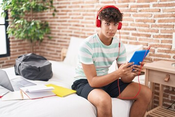 Poster - Young hispanic teenager student sitting on bed studying at bedroom