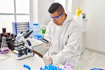 Wall Mural - Young latin man scientist looking cannabis herb with loupe at laboratory