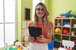 © Krakenimages.com - Young blonde woman teacher using touchpad standing at kindergarten