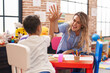 © Krakenimages.com - Teacher and toddler sitting on table high five at kindergarten
