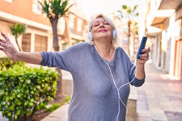 Poster - Middle age blonde woman listening to music and dancing at street