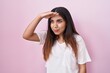 © Krakenimages.com - Young arab woman standing over pink background very happy and smiling looking far away with hand over head. searching concept.