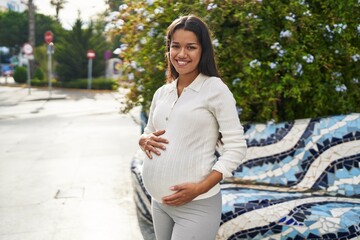 Canvas Print - Young latin woman pregnant smiling confident touching belly at street