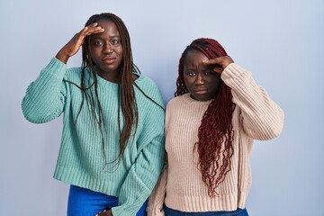 Poster - Two african woman standing over blue background worried and stressed about a problem with hand on forehead, nervous and anxious for crisis