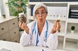 © Krakenimages.com - Middle age woman doctor holding cbd oil making fish face with mouth and squinting eyes, crazy and comical.