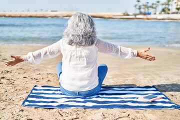 Wall Mural - Middle age woman sitting on towel at seaside