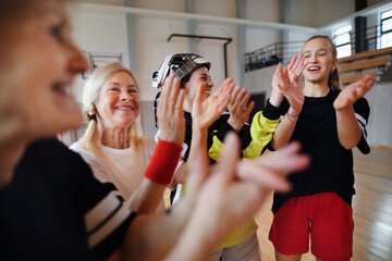 Sticker - Group of young and old cheerful women, floorball team players, in gym cebrating victory.