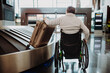 © Halfpoint - Rear view of man on wheelchair at airport with his luggage.
