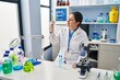 © Krakenimages.com - Young hispanic woman wearing scientist uniform holding test tube at laboratory