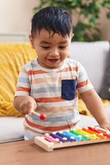 Wall Mural - Adorable hispanic toddler playing xylophone standing at home