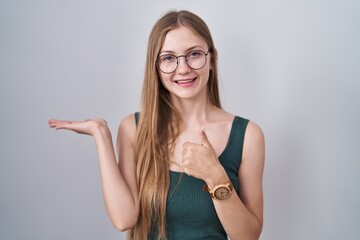 Canvas Print - Young caucasian woman standing over white background showing palm hand and doing ok gesture with thumbs up, smiling happy and cheerful