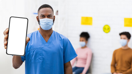 Vaccination Ad. Black Doctor In Medical Mask Showing Smartphone With Blank Screen