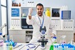 © Krakenimages.com - Young hispanic man with beard working at scientist laboratory angry and mad raising fist frustrated and furious while shouting with anger. rage and aggressive concept.