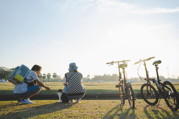 asian couple relax and exercise by cycling bicycle at park with cat in the morning on springtime