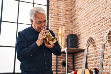 Wall Mural - Senior man musician playing trumpet at music studio