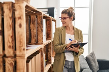 Canvas Print - Young blonde woman psychologist writing on clipboard standing at psychology center