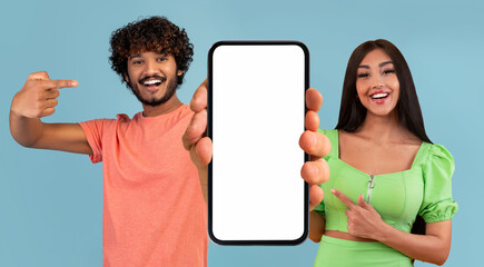 Wall Mural - Check This App. Cheerful Indian Man And Woman Demonstrating Big Blank Smartphone